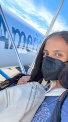 woman in front of american airlines plane with mask and backpack