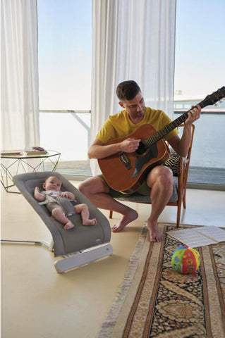 Beba u njihalici dok tata svira gitaru