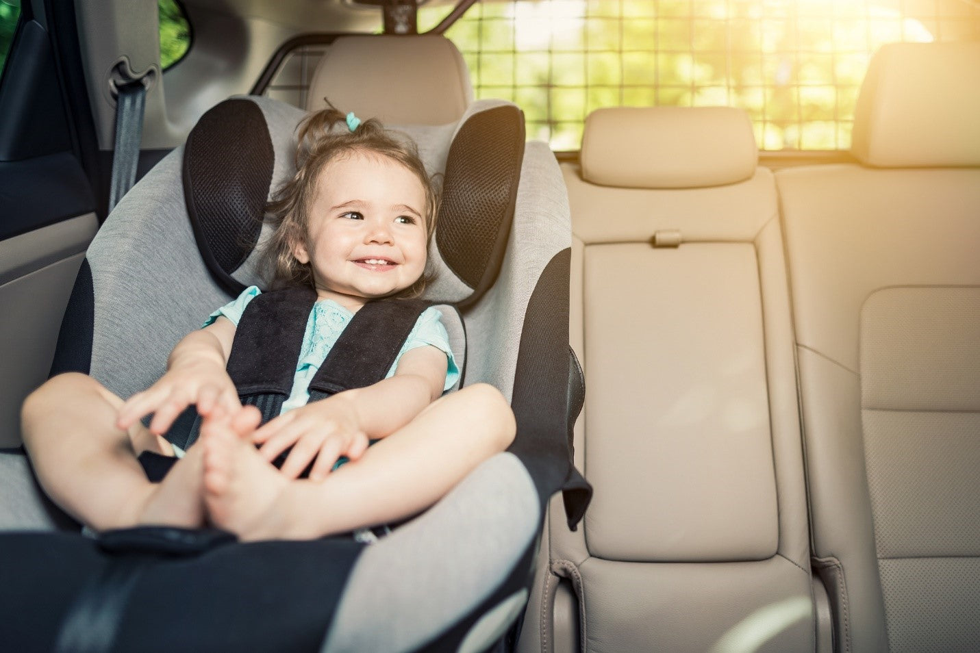 Devojčica sedi u auto sedištu i smeje se