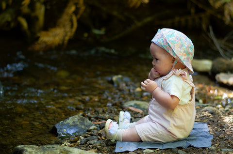 Beba sedi na kamenčićima pored vode