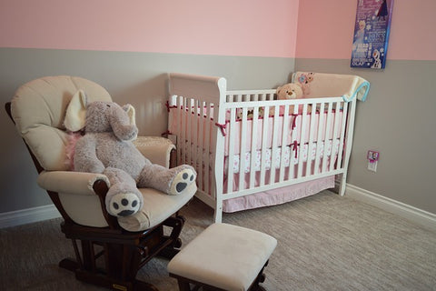 Soba za bebe sa rozo-sivim zidovima u kojoj su kolevka i fotelja