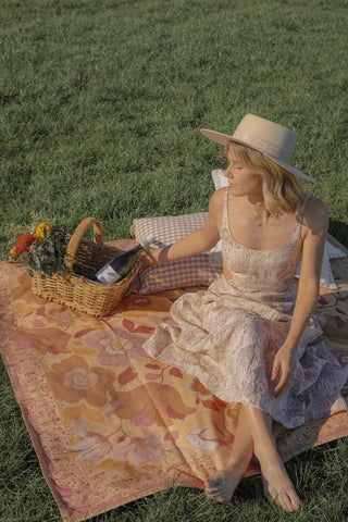 girl sitting on picnic rug in beige linen dress.