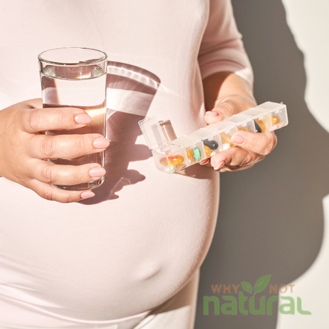 A pregnant woman holds a glass of water and pills, taking vitamin B12 supplements for her health.