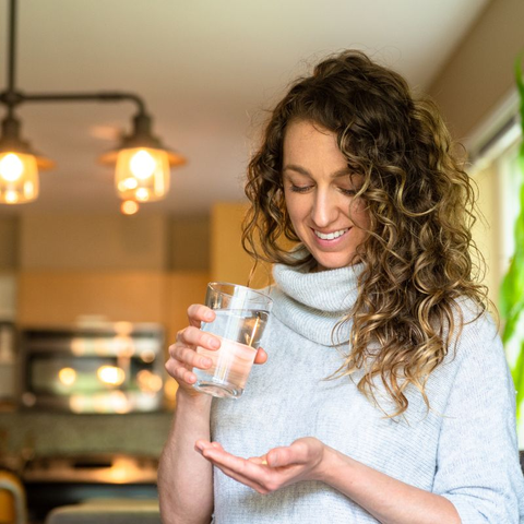 Woman with curly hair taking vitamins for hair growth.