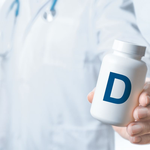 A doctor holding a bottle with the letter D on it.