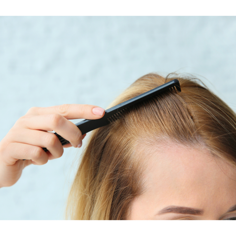 A woman combing her hair, showing some signs of hair loss.