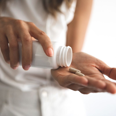 Woman holding bottle of antioxidant pills.