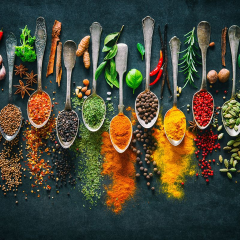 Spices and herbs like cloves, cinnamon, turmeric, oregano in spoons on black background. Natural antioxidants.