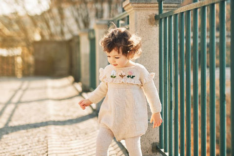 Adorable toddler wearing a knitted romper while playing outside
