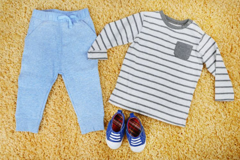 Clothes for a baby boy laid on a colorful background
