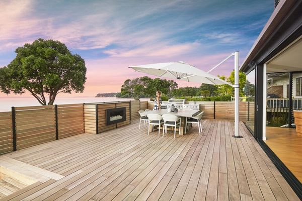 A Eclipse Cantilever umbrella protecting a patio furniture set from the sun, all set up on a deck