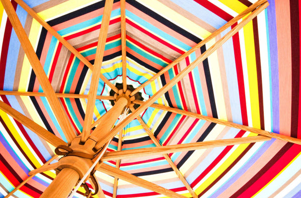 A close-up on a wooden frame patio umbrella with multicolours for summer.
