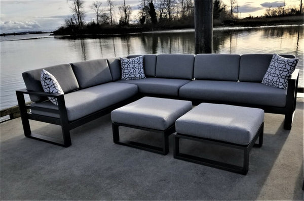 A grey aluminum Sion outdoor sectional positioned next to a lake