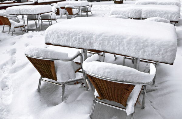 Sets of aluminum tables and chairs covered by snow.