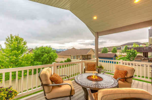 A fire table and patio chairs on a deck looking out at a beautiful view