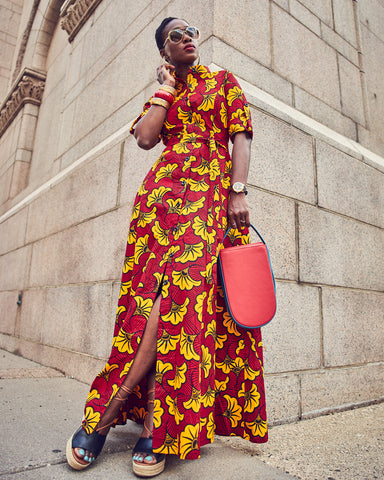 Style influencer Farotelle wearing a colorful maxi printed dress. The dress has a shirt-dress cut and a red and yellow floral pattern. Platform espadrilles sandals and a Tomoli red handbag complete the outfit.