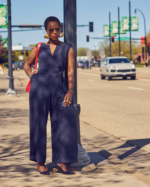 Farotelle wearing Ann Taylor Blue Belted Sleeveless Jumpsuit with M.Gemi blue pumps and red bag as Spring Summer Office Workwear elevated casual style.
