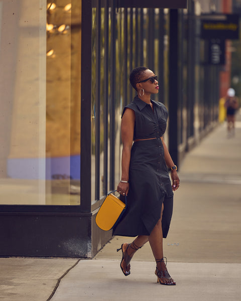 Farotelle wearing Banana Republic black midi cutout dress with sunglasses, black heeled sandals, yellow Tomoli Fitini leather bag as Casual Spring Summer Weekend Datenight Dress Outfit.