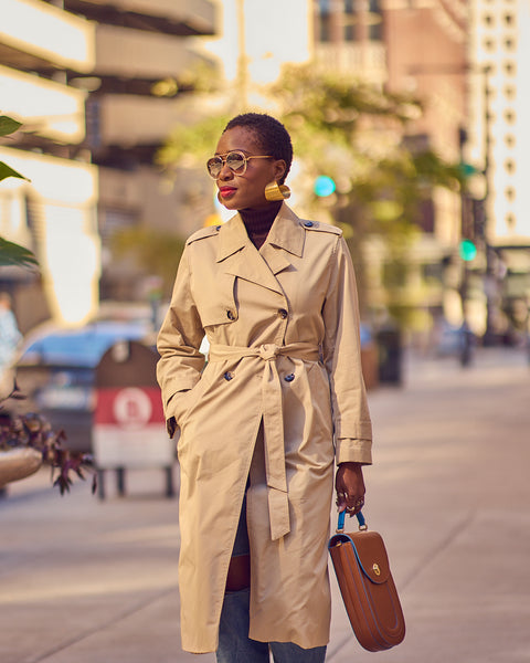 A woman wearing a classic trench coat in a light beige color.