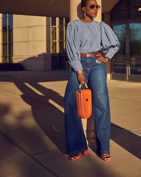 Farotelle wearing Gap blue wide-leg jeans with blue balloon sleeve blouse, Schutz Ully orange strappy sandals and Tomoli Fitini orange bag as Spring Summer elevated casual denim outfit.