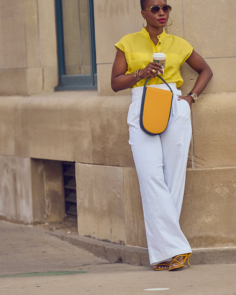 Style Influencer Farotelle in a color-blocked look consisting of white pants, a yellow shirt, yellow sandals and a yellow bag.