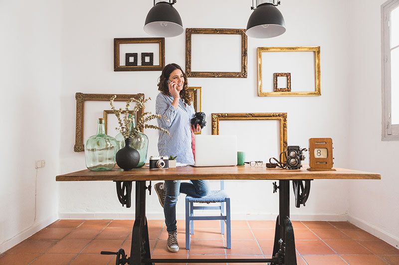 wall of frames woman standing in front of table
