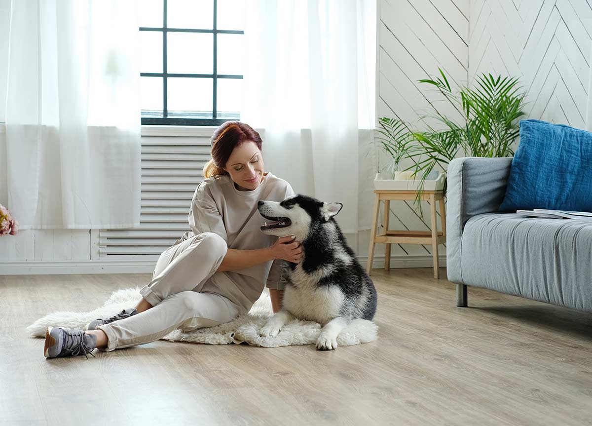 woman playing with dog on floor