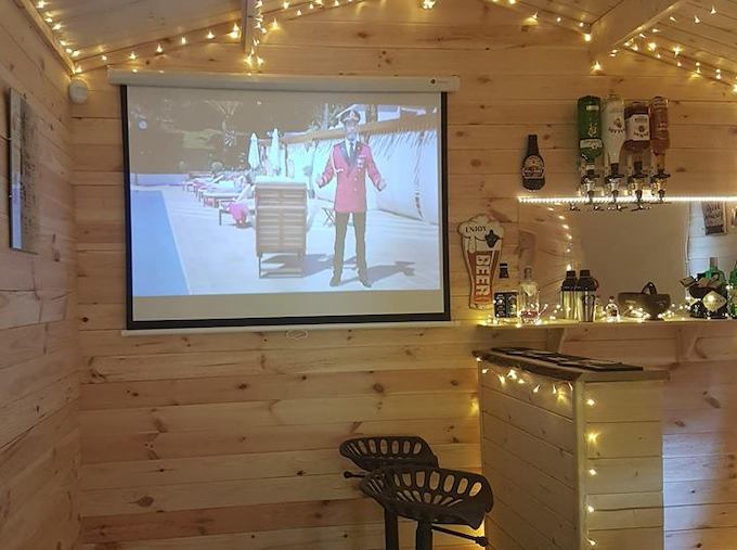 Interior of log cabin turned home cinema experience with fairy lights and projector