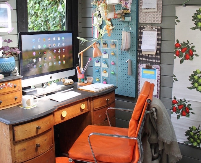 Image of Joanna's colourful garden office with orange chair and wall art turned storage