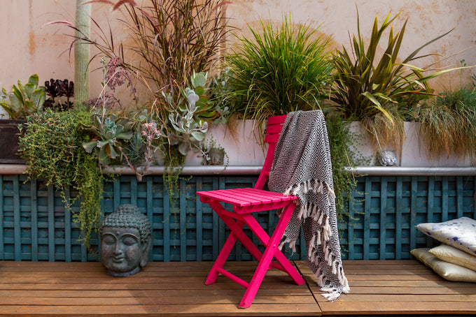 Pink chair, buddha head and a green trellis in outdoor garden