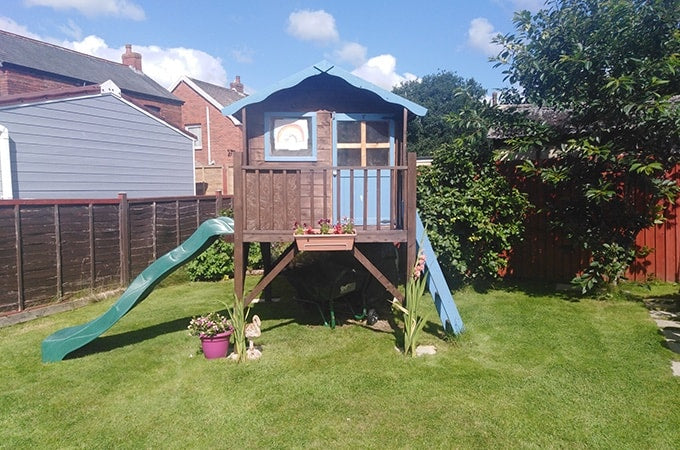 Brown and blue tower playhouse with green slide