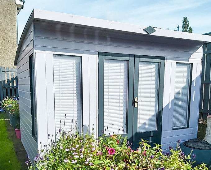 Blue and navy painted summer house with blinds covering windows