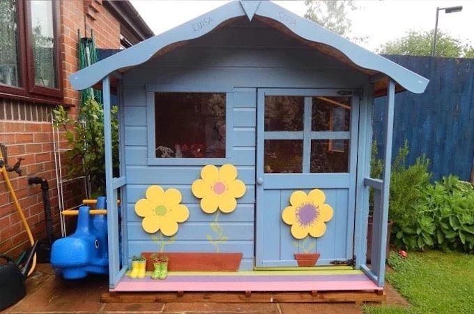 Blue Waltons playhouse with yellow flowers