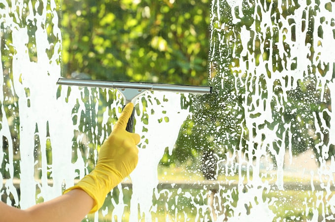 Person cleaning windows indoors with squeegee