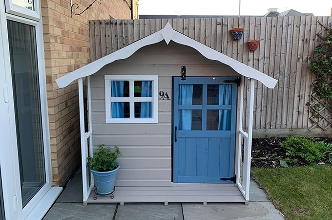 Grey and cream playhouse with sign saying '9a'