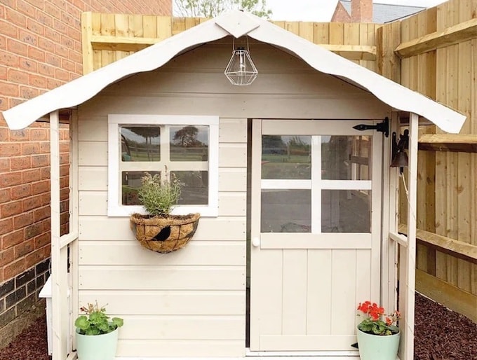 Cream and white playhouse with hanging baskets and potted plants