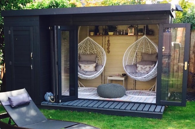 Dark blue painted summerhouse with floating egg chairs