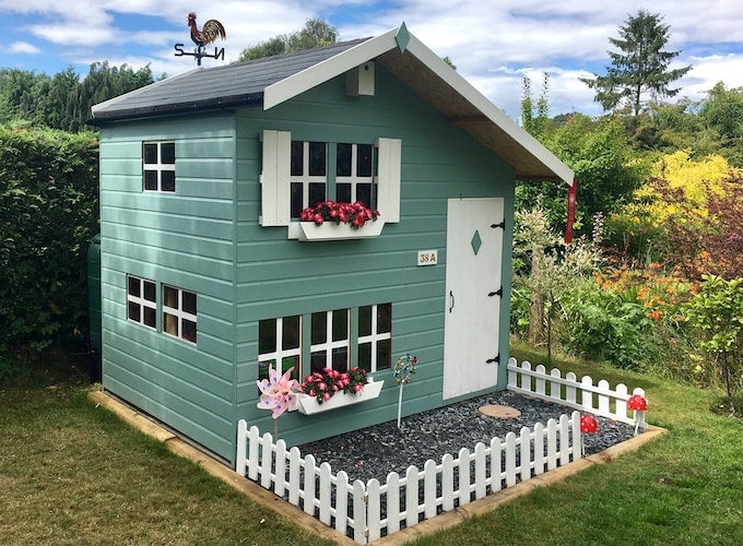 Green painted Waltons double storey playhouse with guttering and white windows and doors