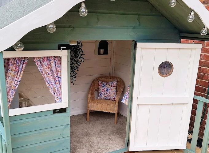 Green and white playhouse with carpet and chair