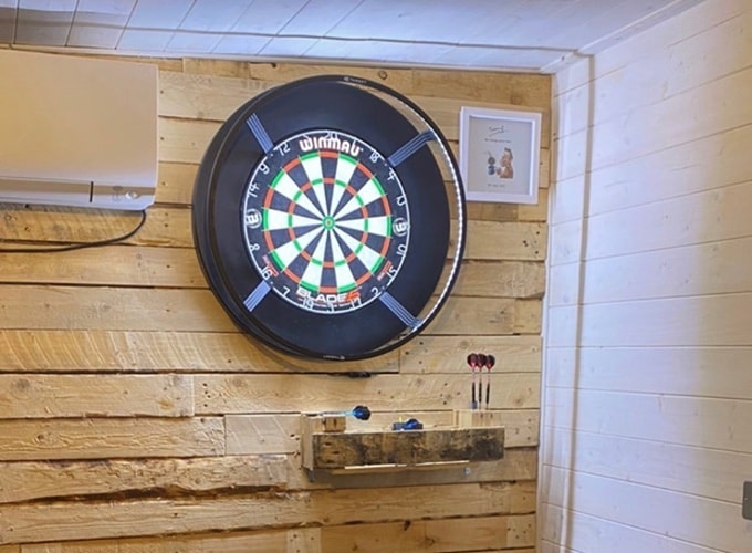 Interior of Waltons insulated garden room with wood panelling walls and dart board