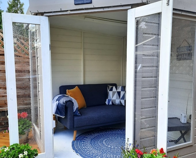 Interior of painted grey summerhouse with blue rug and blue sofa