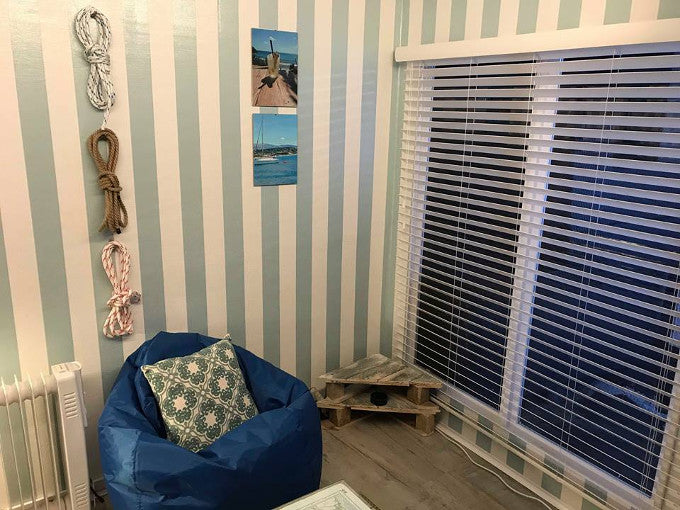 Interior of summer house with blue beanbag and striped wallpaper