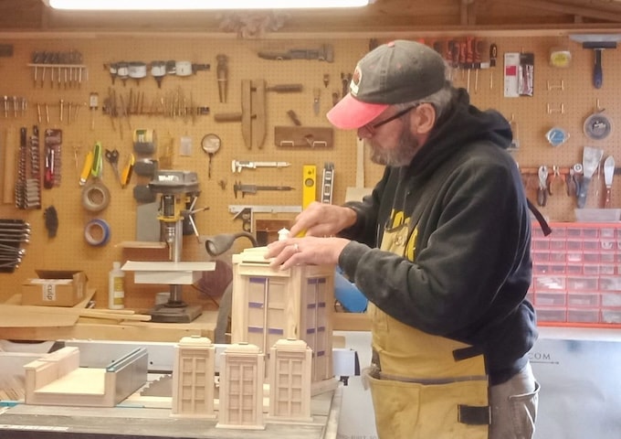 Man carving wooden TARDIS in shed studio