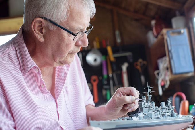 Man painting model boat in shed workshop