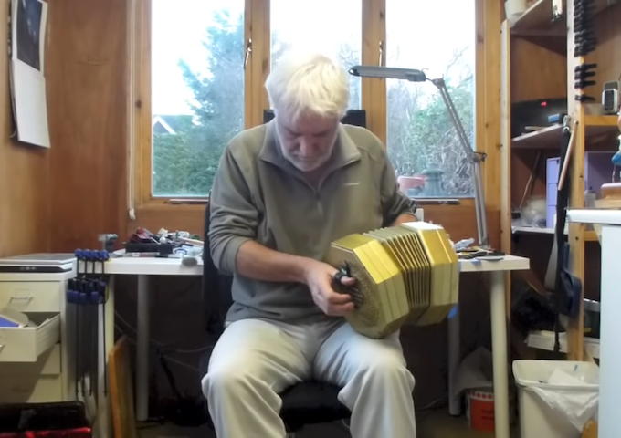 Man playing concertina in garden shed