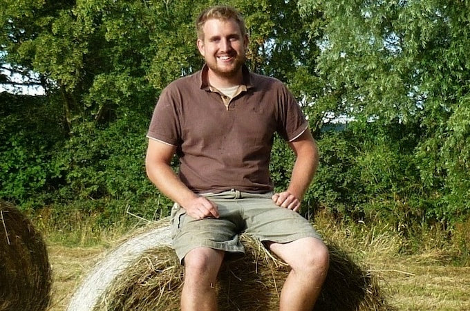 Man sitting on top of hay bale