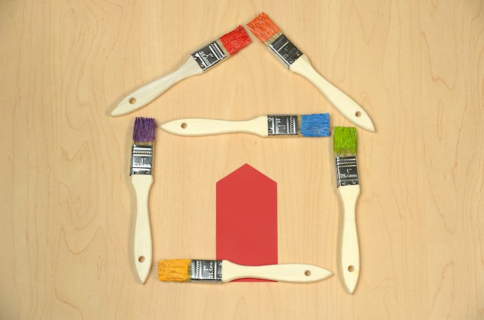 Paintbrushes lying on the floor creating the outline of a house