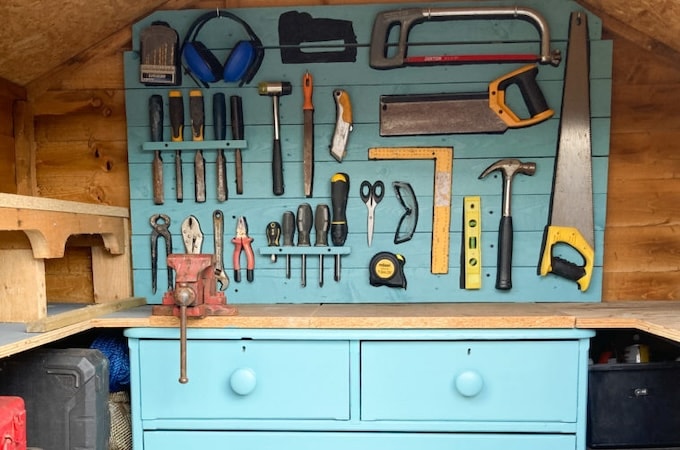 Interior back wall of shed painted blue with tool hooks