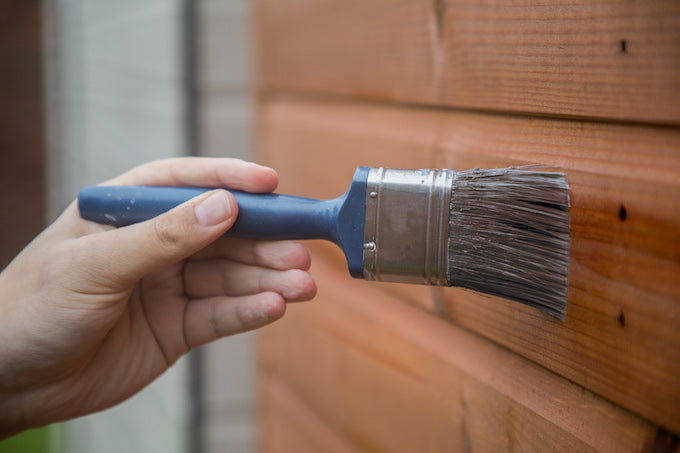 Hand applying coat of preservative on wood