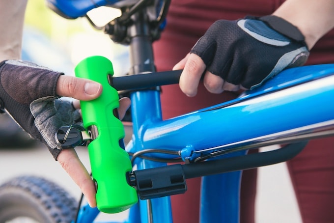 Person securing bicycle with D-shaped bike lock